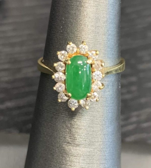 18K Y/G LADIES JADE AND DIAMOND RING FEATURING ONE OVAL SHAPE JADE CENTER STONE 7.5MM X 4 MM SURROUNDED BY .28 PTS OF ROUND BRILLIANT CUT DIAMONDS; SIZE 4.25. 2.0 DWT