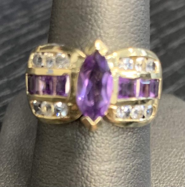 14K Y/G LADIES AMETHYST AND DIAMOND RING FEATURING AN AMETHYST MARQUISE AS A CENTER STONE AND EMERALD CUT AMETHYSTS SIDE STONES, AS WELL AS .48 PTS OF ROUND BRILLIANT CUT DIAMONDS ON THE SIDE. 3.5 DWT.