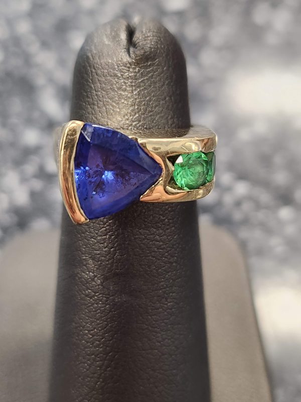 14K Y/G LADIES TANZANITE RING WITH AN APROX. 2-2.50 CARAT TRILLION CUT TANZANITE WITH 0.60 PTS OF TSAVORITE RBC SIDE STONES WEIGHING 6.4 DWT.